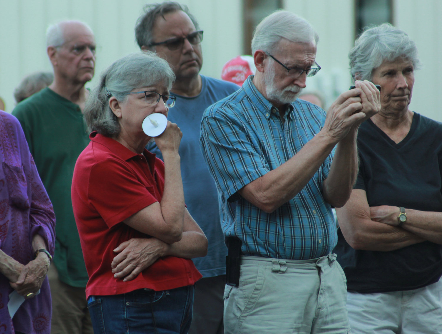 From left, Connie McAdams and Gary Simpson listen as Sheila Fleming sings “Calling All Angels” at the Chatham County vigil for recent mass shootings on Sunday, May 29 in Pittsboro.